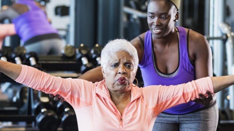 Trainer coaching senior citizen weightlifting.